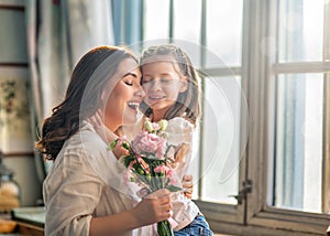 Daughter giving mother bouquet of flowers