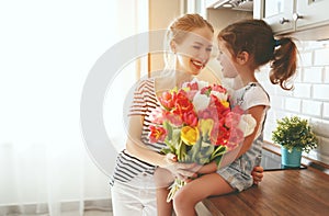 Happy mother`s day! child daughter gives mother a bouquet of f