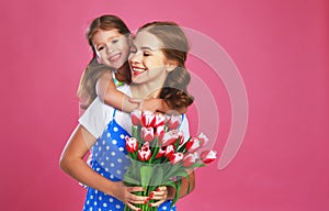 Happy mother`s day! child daughter gives mother a bouquet of flowers on color pink background