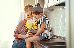 Happy mother`s day! child daughter   gives mother a bouquet of flowers to narcissus and gift