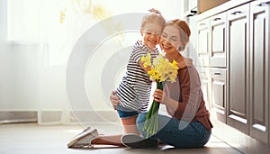 Happy mother`s day! child daughter   gives mother a bouquet of flowers to narcissus and gift