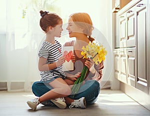 Happy mother`s day! child daughter   gives mother a bouquet of flowers to narcissus and gift