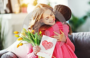 Happy mother`s day! child daughter gives mother a bouquet of flowers to tulips and postcard