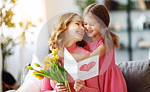 Happy mother`s day! child daughter gives mother a bouquet of flowers to tulips and postcard