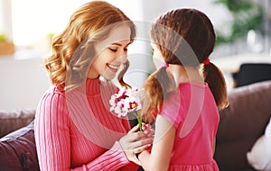 Happy mother`s day! child daughter gives mother a bouquet of flowers to tulips and postcard