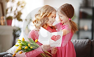 Happy mother`s day! child daughter gives mother a bouquet of flowers to tulips and postcard