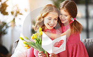 Happy mother`s day! child daughter gives mother a bouquet of flowers to tulips and postcard