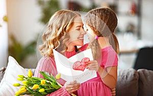 Happy mother`s day! child daughter gives mother a bouquet of flowers to tulips and postcard