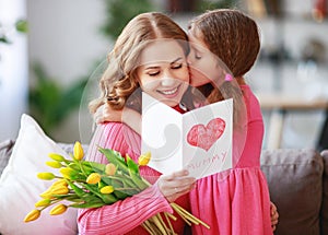 Happy mother`s day! child daughter gives mother a bouquet of flowers to tulips and postcard