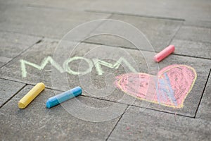 Happy Mother`s Day. Child draws for her mother a picture surprise of crayons on the asphalt. LOVE MOM