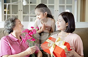 Happy mother`s day  . Child and  mother congratulating grandmother  giving her flowers and  gift box