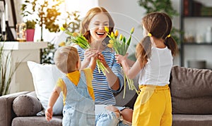 Happy mother`s day! Children congratulates moms and gives her a gift and flowers