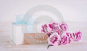 Happy Mother`s Day concept. Gift box with flowers and greeting card on white wooden background