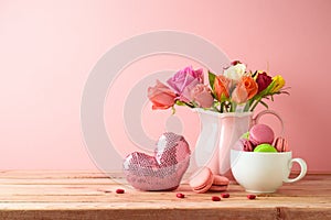 Happy Mother`s day concept. Macaroons french cookies, heart shape and rose flower bouquet on wooden table over pink background