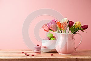 Happy Mother`s day concept. Macaroons french cookies and rose flower bouquet on wooden table over pink background
