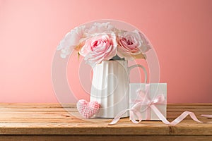 Happy Mother's day concept with rose flowers, heart shape and gift box on wooden table over pink background