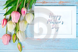 Happy mother`s day concept. white picture frame and flower on wooden background