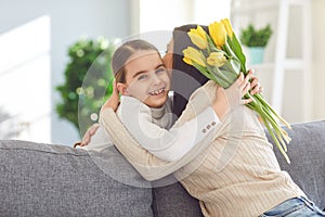 Happy mother`s day. Daughter congratulates hugs his mother holds a bouquet of flowers in the room.