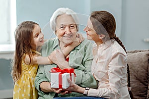 Happy Mother's Day. Daughter and granddaughter congratulate mother and grandmother, gives her a gift.