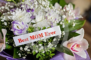 Happy Mother`s Day gift, and Best Mom Ever greeting card on table.Beautiful big bouquet with orchids flowers and