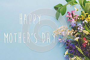 Happy Mother`s day greeting card. Colorful spring flowers border on blue background flat lay with greeting text. Floral greeting