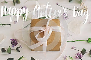 Happy mother`s day greeting card. Happy mother`s day text and gift box, lilac, roses flowers and eucalyptus leaves on white wood