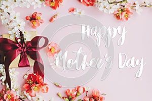 Happy mother`s day greeting card. Happy mothers day text and gift box with red and white flowers on pink background flat lay.