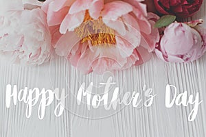 Happy mother`s day greeting card. Happy mother`s day text and  peony floral border on white wood. Stylish floral greetings.