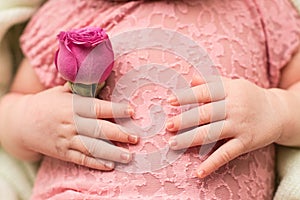Happy Mother`s day. hands of the newborn baby with pink rose flower