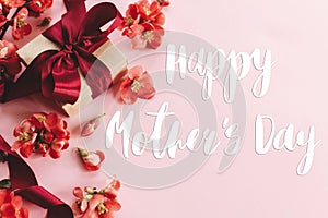 Happy mother`s day. Happy mothers day text and gift box with red flowers on pink background flat lay. Stylish floral greeting car