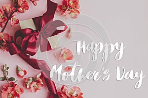 Happy mother`s day. Happy mothers day text and gift box with red flowers on pink background flat lay. Stylish floral greeting car