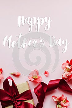 Happy mother`s day. Happy mothers day text and gift box with red flowers on pink background flat lay. Stylish floral greeting car