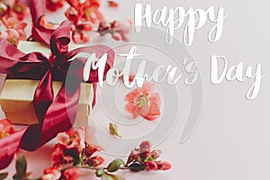 Happy mother`s day. Happy mothers day text and gift box with red flowers on pink background. Stylish floral greeting card.