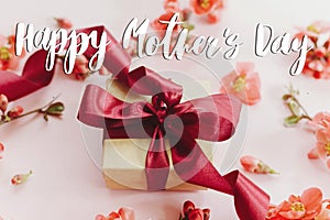 Happy mother`s day. Happy mothers day text and gift box with red flowers on pink background. Stylish floral greeting card.