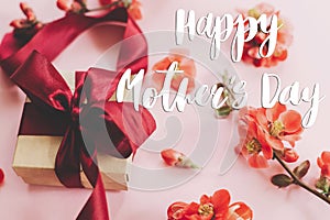 Happy mother`s day. Happy mothers day text and gift box with red flowers on pink background. Stylish floral greeting card.