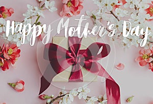 Happy mother`s day. Happy mothers day text and gift box with red and white flowers on pink background flat lay. Stylish floral