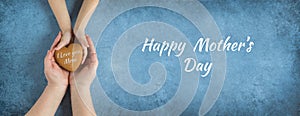 Happy mother`s day.Heart in the hands of daughter and mother on a blue background.I love you.Love and health in the family.Banner