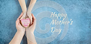 Happy mother`s day.Heart in the hands of daughter and mother on a blue background.I love you.Love and health in the family.Banner