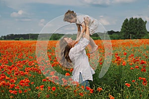 Happy Mother's Day. Little boy and mother is playing in a beautiful field of red poppies
