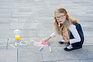 Happy Mother`s Day. A little girl draws for her mother a picture surprise of crayons on the asphalt.