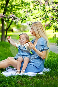 Happy mother`s day. Little girl hugs her mother in the spring cherry garden. Portrait of happy mother and daughter among pink