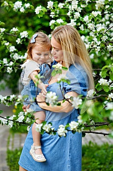 Happy mother`s day. Little girl hugs her mother in the spring cherry garden. Portrait of happy mother and daughter among white