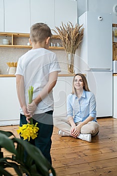 Happy mother`s day! little son gives flowers to mom, boy congratulates mom, flowers in the hands of a boy, yellow daffodils, happy