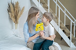 Happy mother`s day! little son gives flowers to mom, boy congratulates mom, flowers in the hands of a boy, yellow daffodils, happy