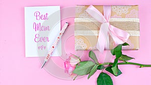 Mother`s Day overhead with roses, Best Mom Ever card and gift on pink table.