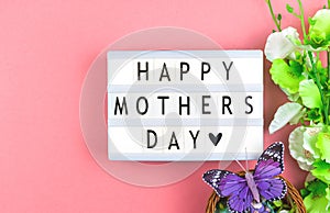 Happy Mother& x27;s Day text background, text message on a lightbox, pink workspace with spring flowers, holiday concept