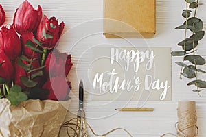 Happy mother`s day. Happy mother`s day text on card and red tulips, gift, pencil, scissors and twine on rustic white wood, flat