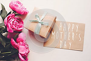 Happy mother`s day text on craft card and pink peonies bouquet w