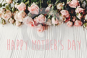 Happy Mother`s Day text sign at pink small roses on wooden background, space for text. Tender Flower border, Floral greeting card