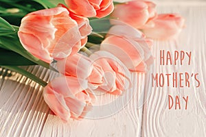Happy mother`s day text sign on pink tulips on white rustic wood